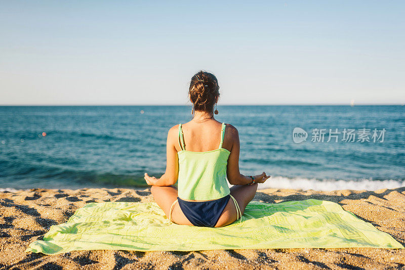 在海边做瑜伽的女人。宁静的场景/积极的生活理念。